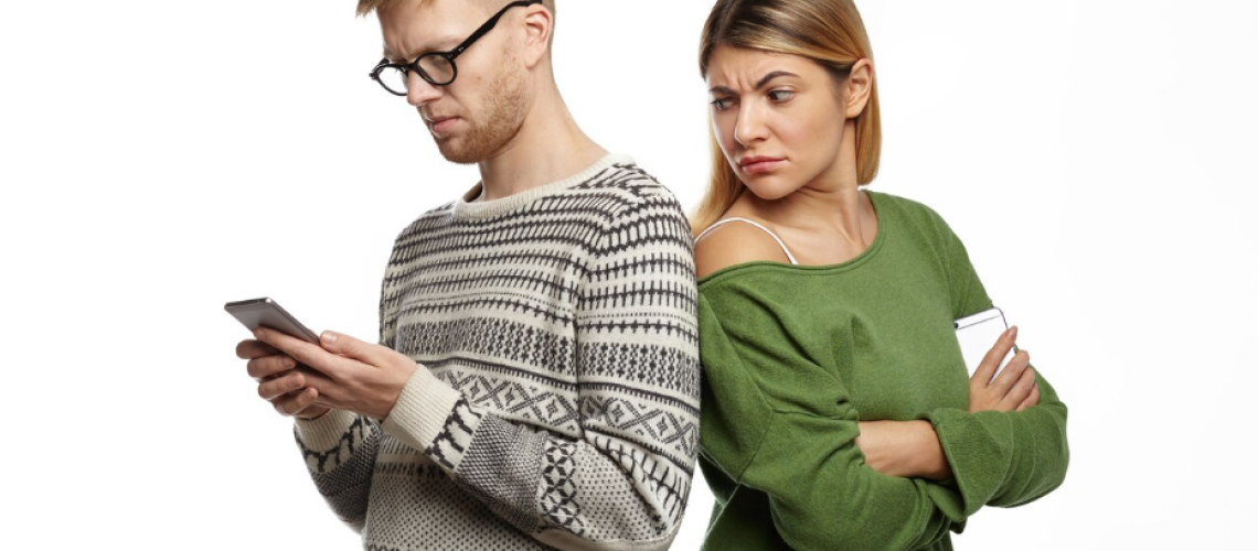 Para w konflikcie – kobieta patrzy z podejrzliwością na telefon partnera. Czy zdrada ma wpływ na wysokość alimentów?